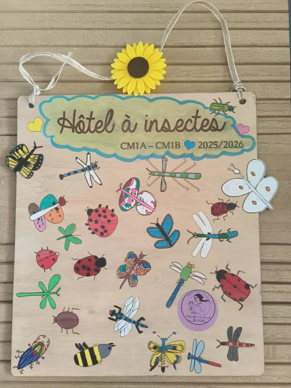 Le panneau d'hôtel à insectes terminé, suspendu par une cordelette et surmonté d'un tournesol